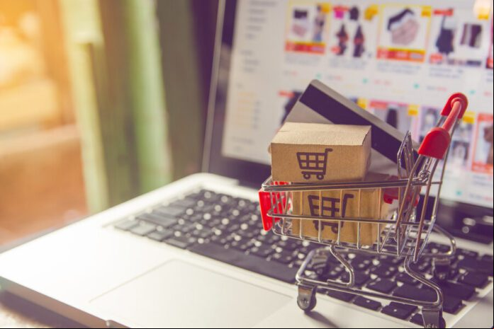 Shopping online concept - Parcel or Paper cartons with a shopping cart logo in a trolley on a laptop keyboard. Shopping service on The online web. with payment by credit card and offers home delivery.